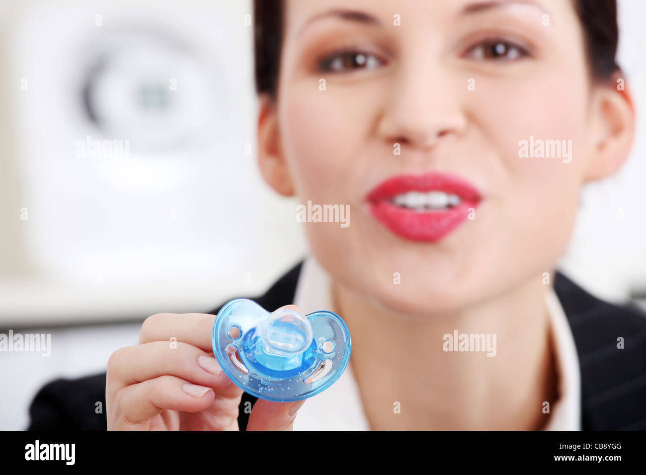 Pretty caucasian businesswoman giving a baby`s dummy to her child Stock